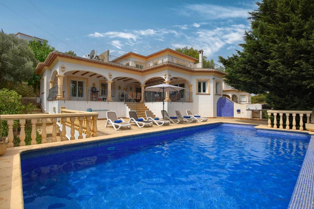 a villa with a swimming pool in front of a house at Anngo in Jávea