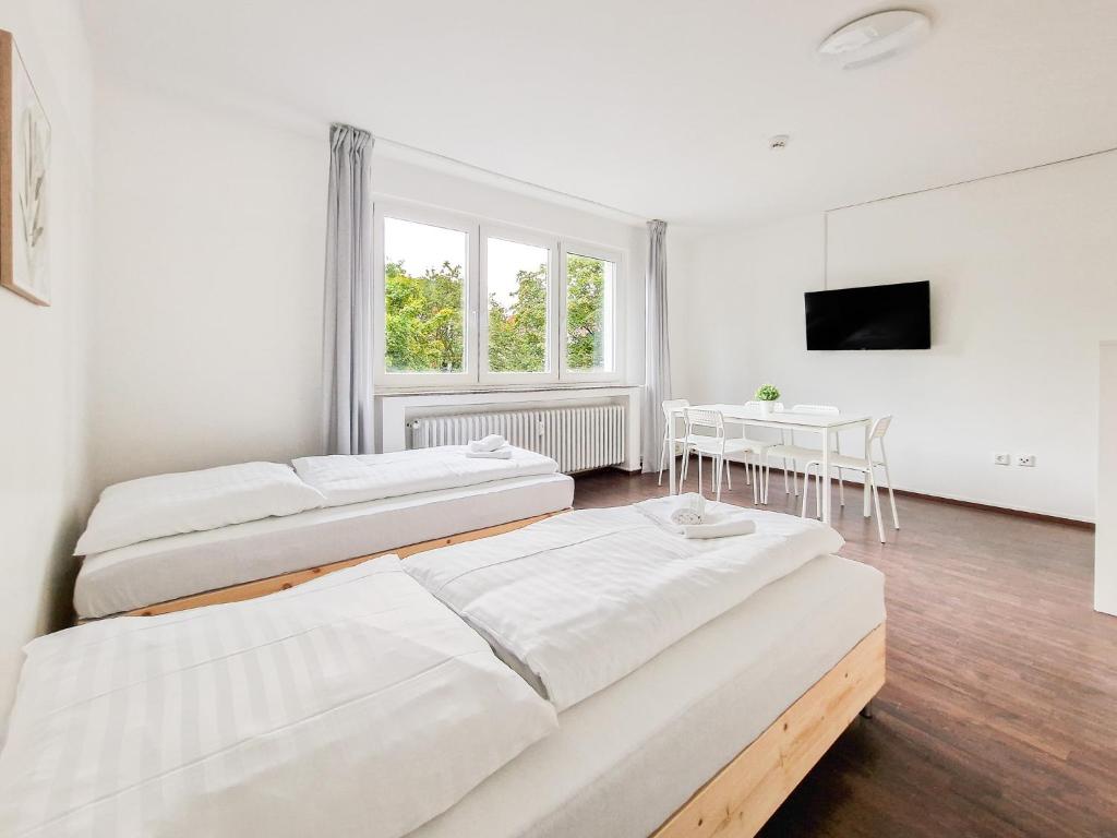 Habitación con 2 camas, mesa y TV. en RAJ Living - 1 or 3 Room Apartments - 30 Min Messe DUS, en Duisburg