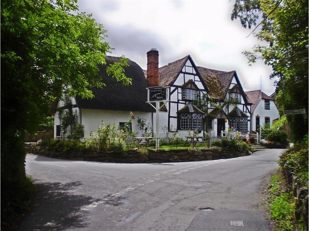 an old house with a thatched roof on a street at White Horse Inn in Woolstone