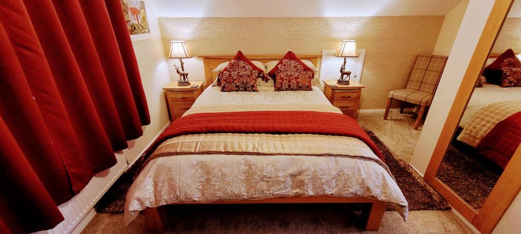 una camera da letto con un letto con tende rosse e uno specchio di Self catering upper floor flat at Woodend house a Balmacara