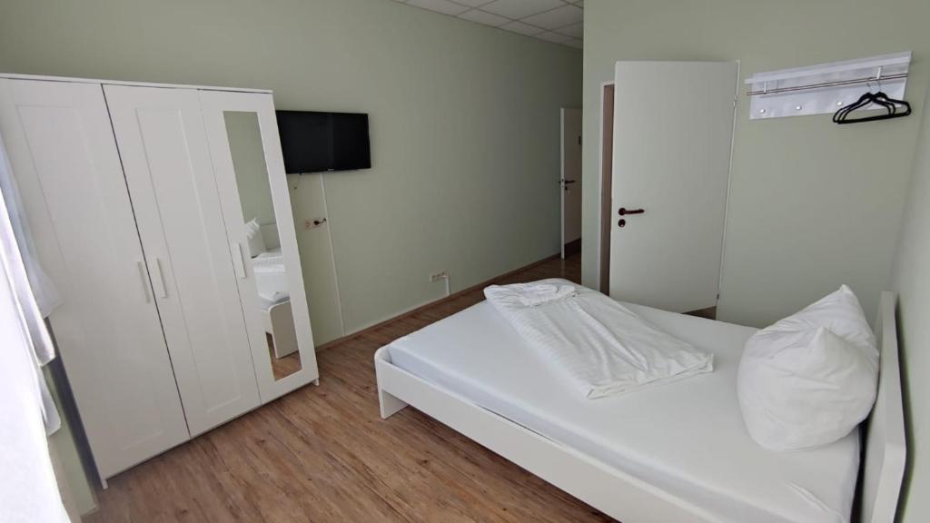 Schlafzimmer mit einem weißen Bett und einem Spiegel in der Unterkunft 3 Bett Zimmer in Ramstein-Miesenbach