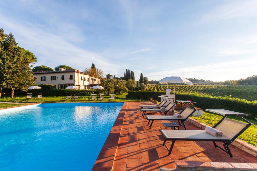 una fila de sillas sentadas junto a una piscina en Fattoria Montignana, en San Casciano in Val di Pesa