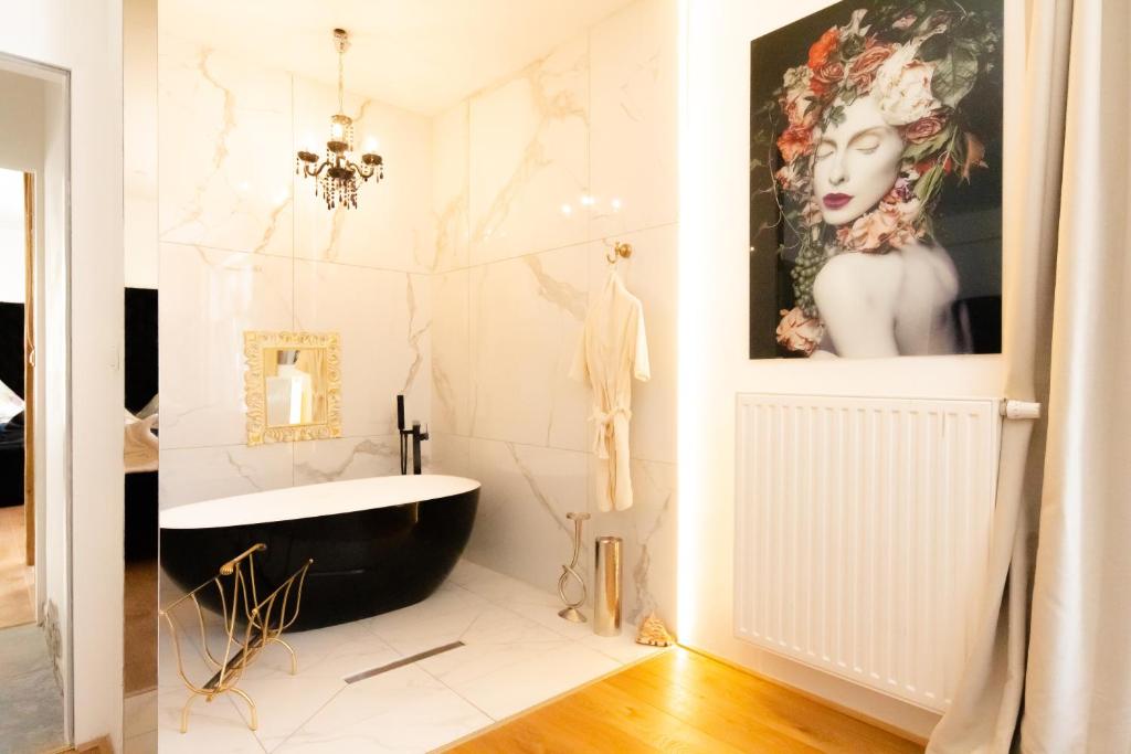 bagno con vasca nera e piastrelle bianche. di XuBa ApartmentRooms Messe Wien Prater a Vienna