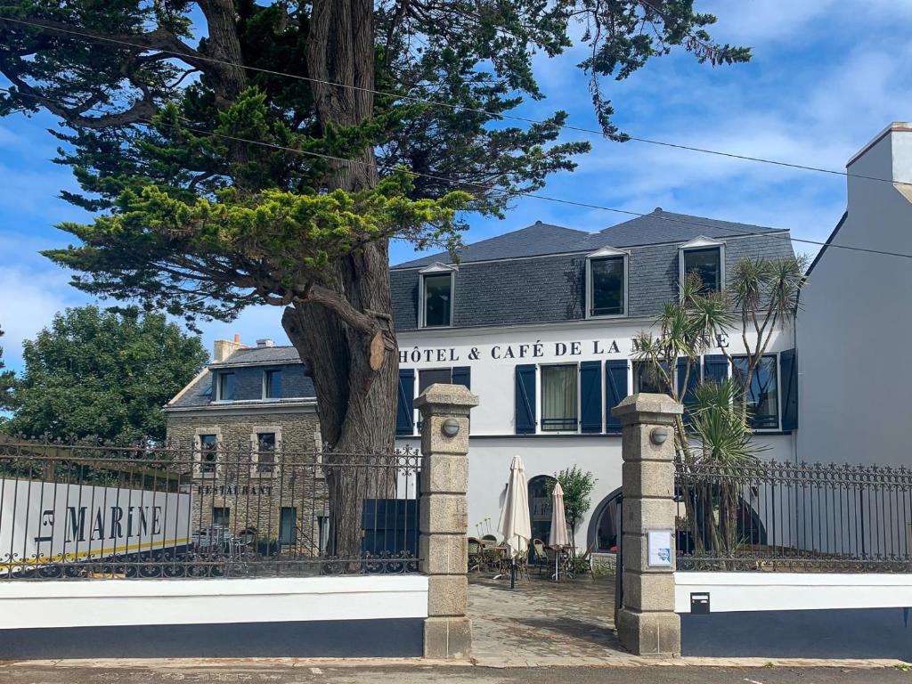 una casa con una valla y un árbol en HOTEL LA MARINE, en Groix