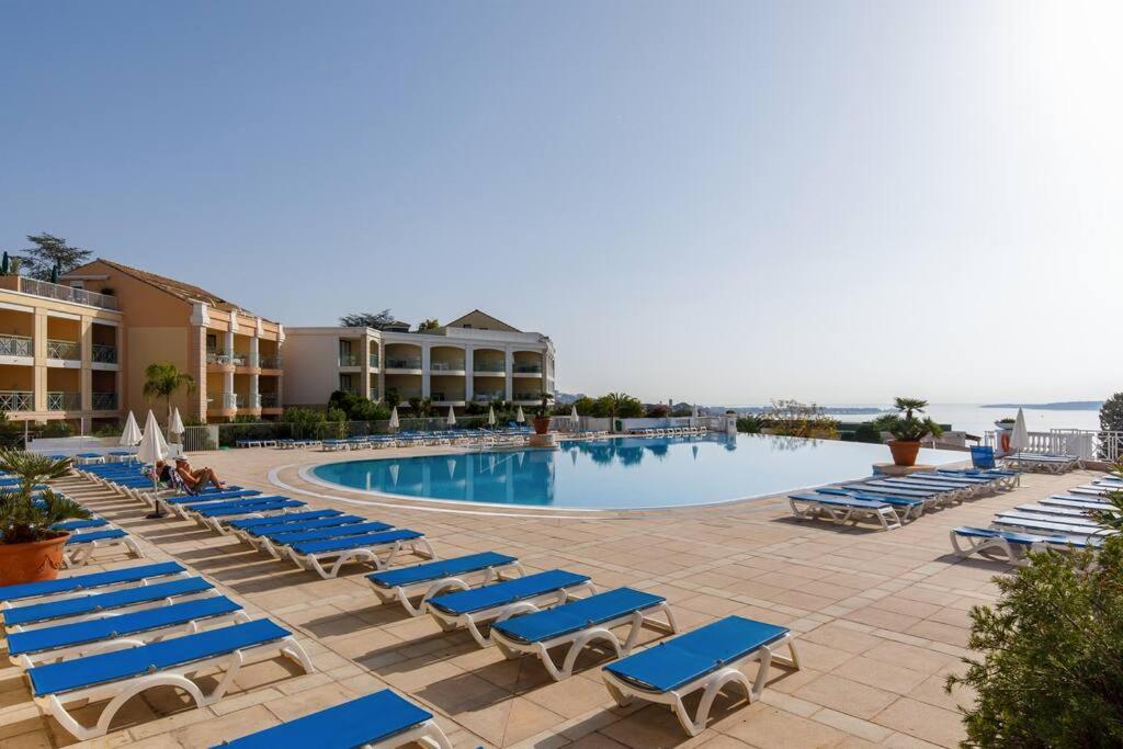 une piscine avec des chaises longues bleues et un complexe dans l'établissement Chagall 3 étoiles YourHostHelper, à Cannes