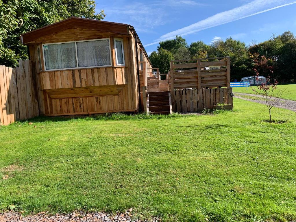 a cabin in a yard next to a fence at Shambala Country Cabin in Kentisbeare