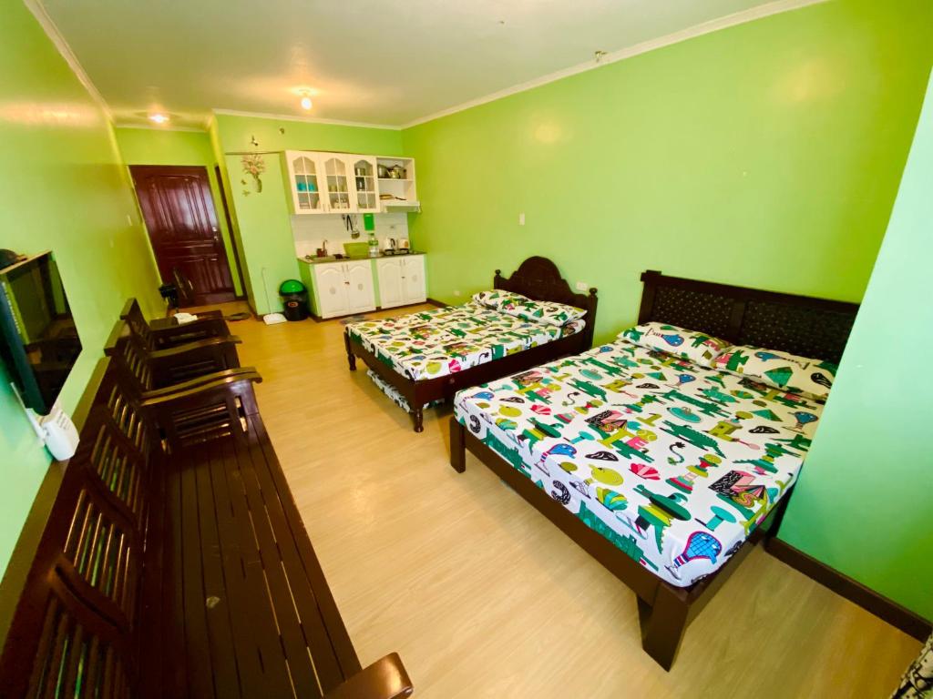 two beds in a room with green walls at Albergo Hotel - Studio Condo Unit - Baguio Transient in Baguio