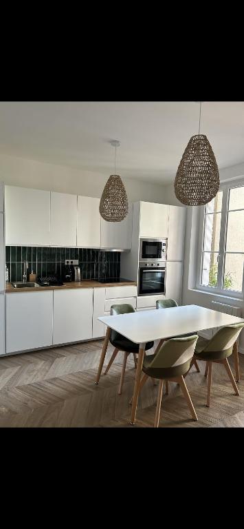 une cuisine blanche avec une table et des chaises dans l'établissement La marine 2, à Deauville