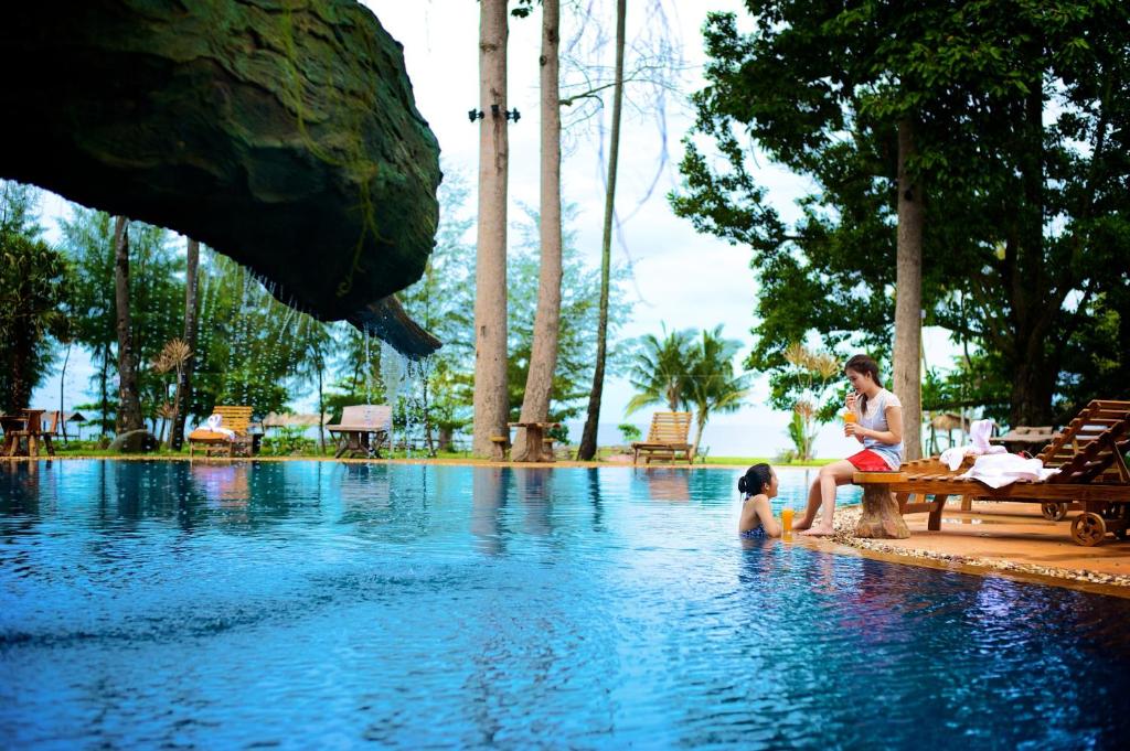 un hombre y un niño sentados en una piscina en Blues River Resort, en Chao Lao Beach