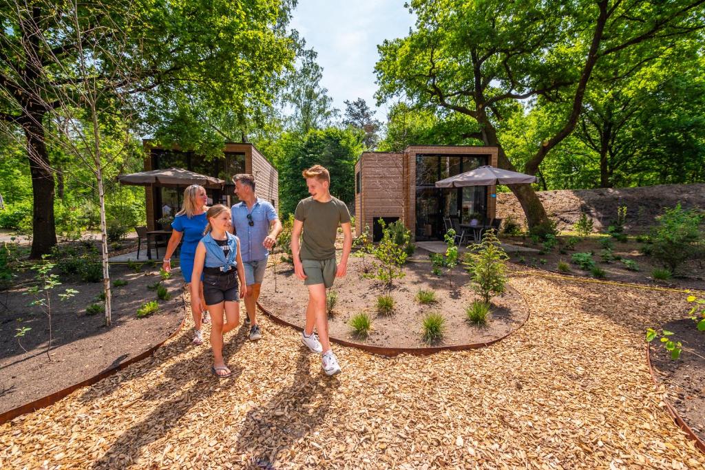 a family standing in front of a garden at Comfort Rooms by EuroParcs De Hooge Veluwe in Arnhem