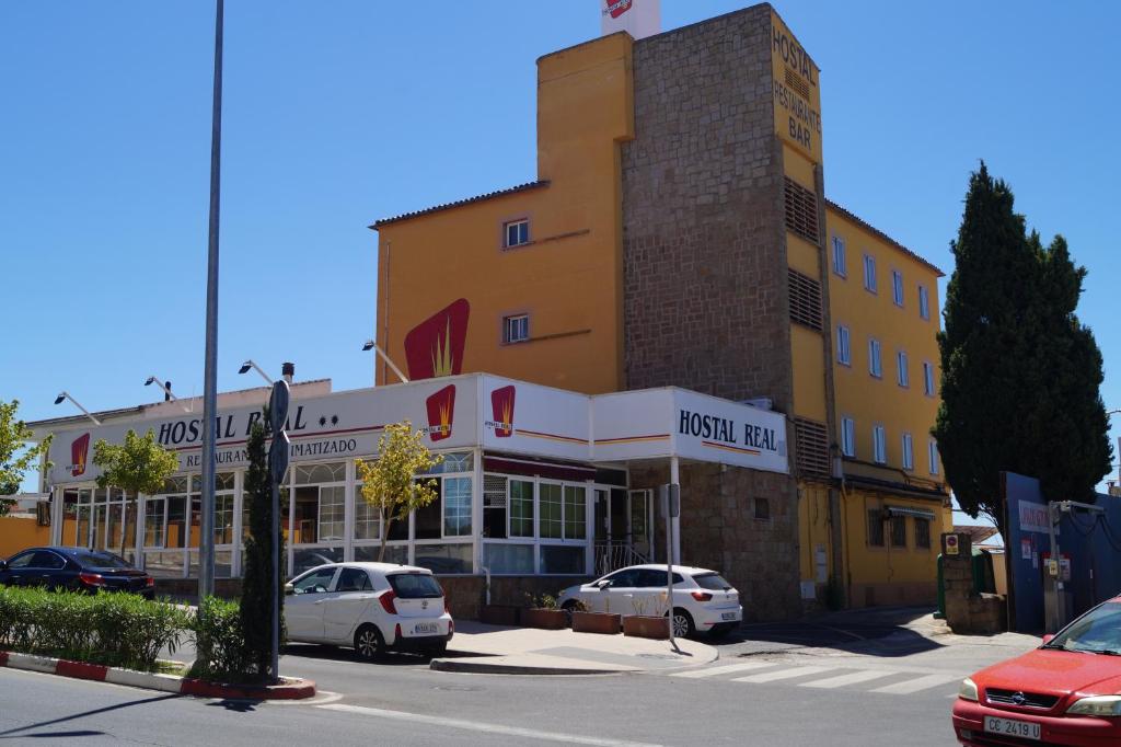 a hotel with cars parked in front of a building at Hostal Real in Plasencia