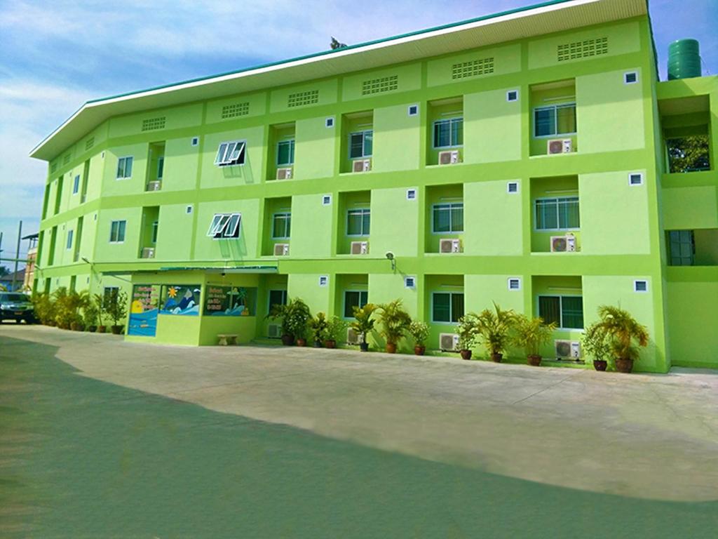 a large green building with palm trees in front of it at Sorworakit Hotel in Bangsaen