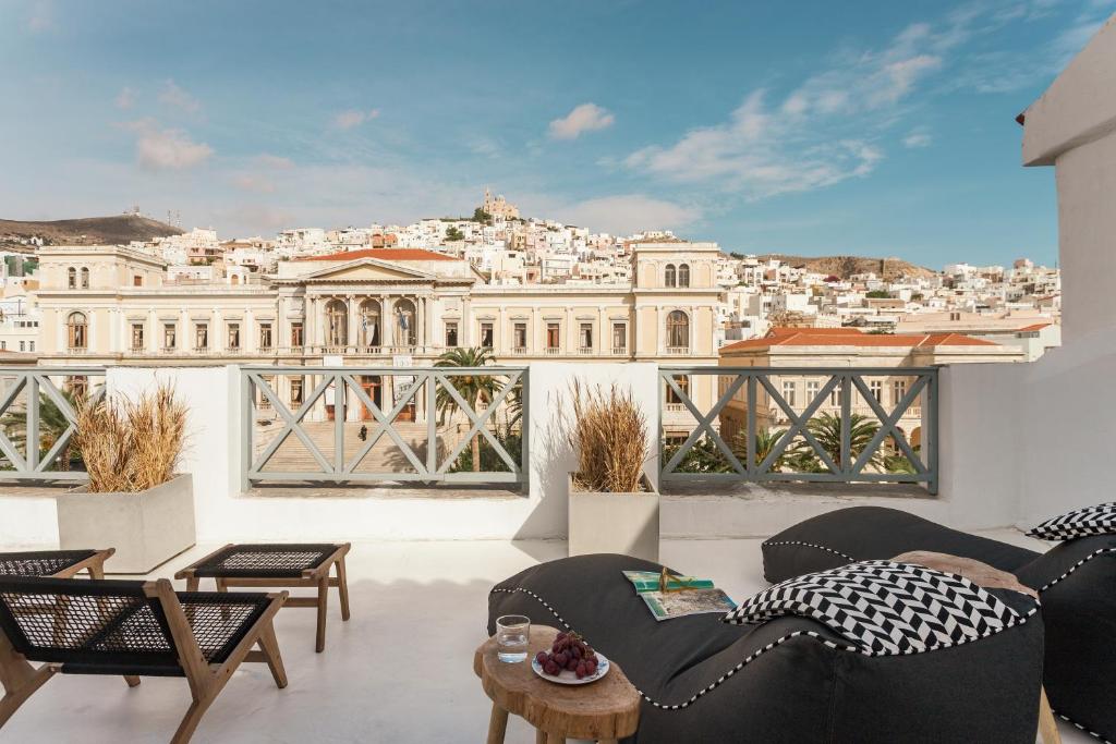 a balcony with furniture and a view of a city at SYROS SOUL LUXURY SUITES in Ermoupoli