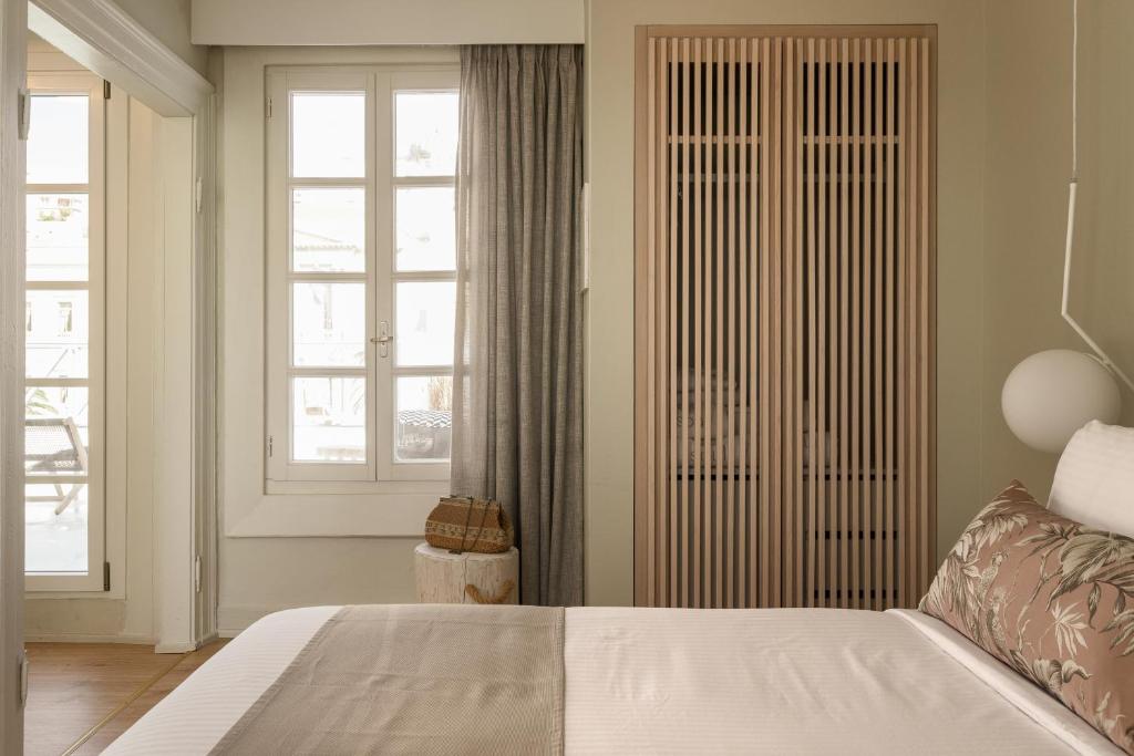 a bedroom with a white bed and a window at SYROS SOUL LUXURY SUITES in Ermoupoli