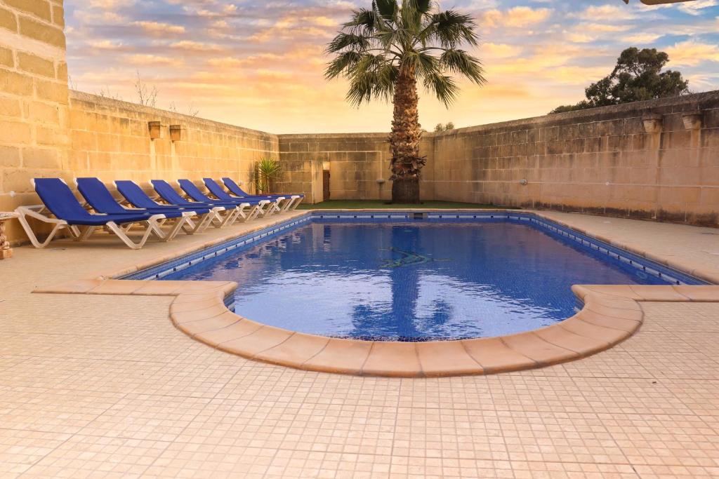 een zwembad met ligstoelen en een palmboom bij Centre Island Holiday Home with private pool and hot tub in Kerċem