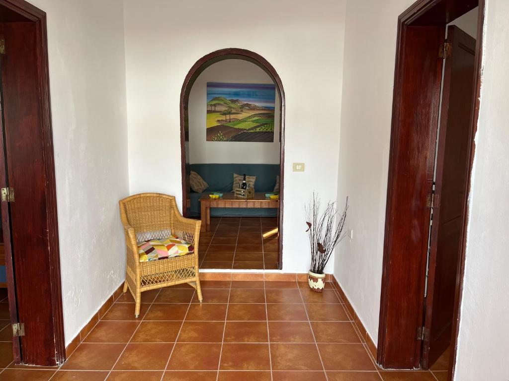 a hallway with a wicker chair and a table at Casa de campo Yuco in Tinajo