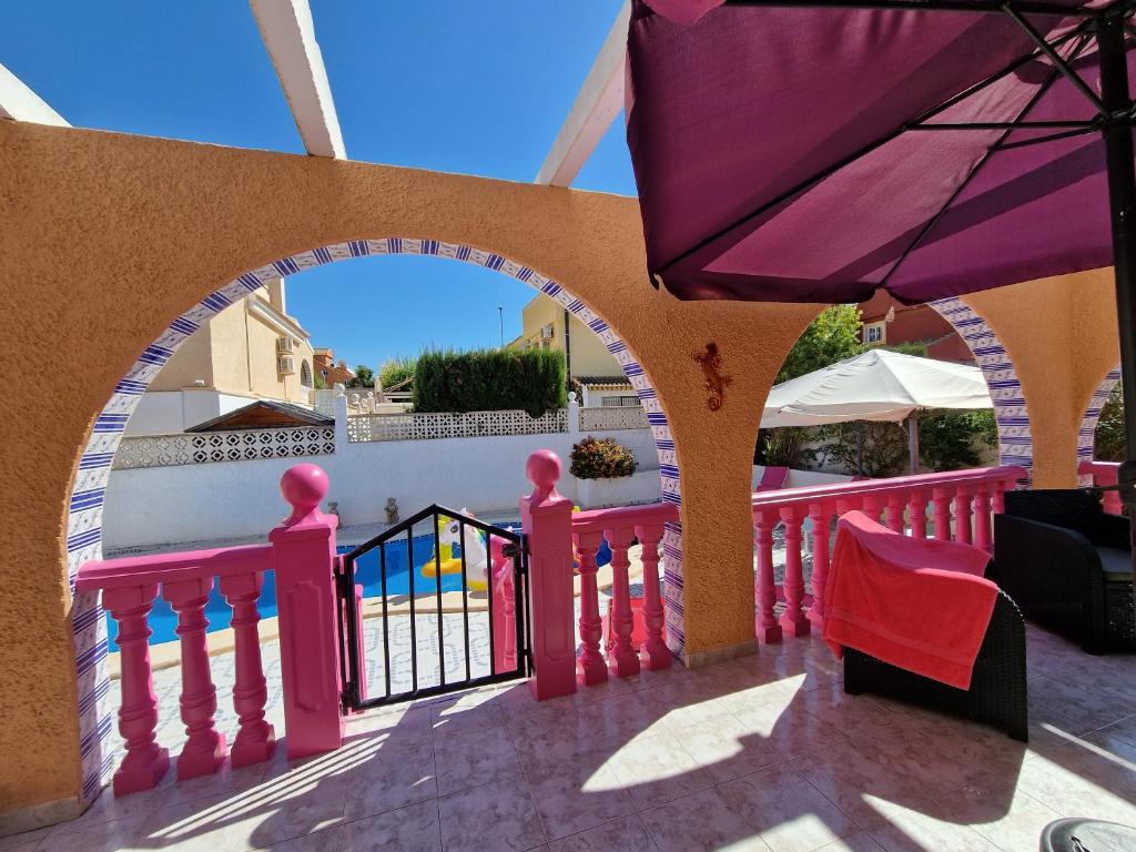 a patio with a pink fence and an umbrella at Villa pink Ambience in Mazarrón