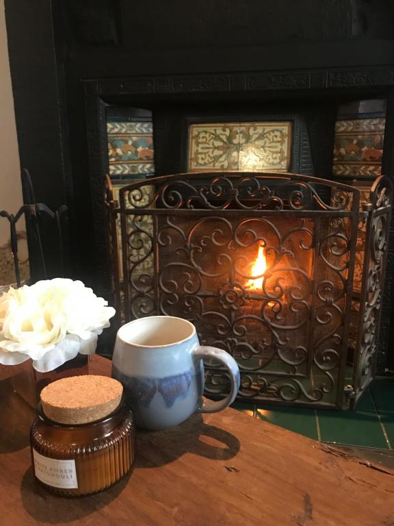 a coffee cup sitting on a table in front of a fireplace at Mill Cottage Modern Boutique Cosy Home in Lake District Village near Scafell in Gosforth