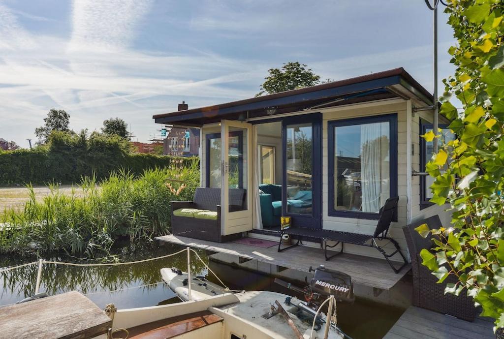 a tiny house on a boat in the water at Woonark Westeinder with kayaks close to Schiphol Airport in Aalsmeer