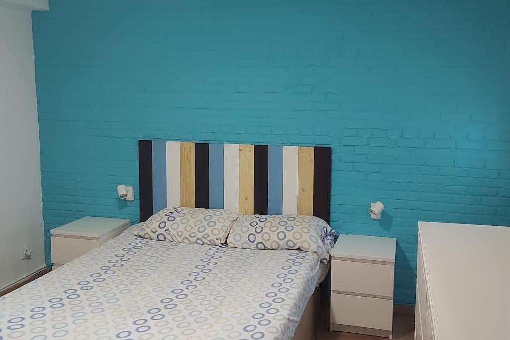 a bedroom with a bed with a blue wall at Precioso piso-apartamento en barrio de Zaragoza in Zaragoza