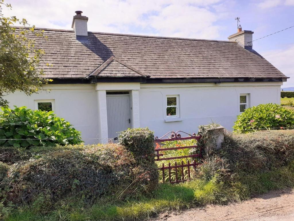 Uma casa branca com um banco à frente. em Lackaroe Cottage em Garrykennedy