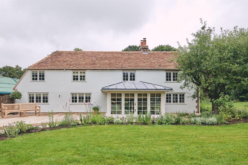 a white house with a bench and a yard at Bridlepath Cottage in West Woodhay