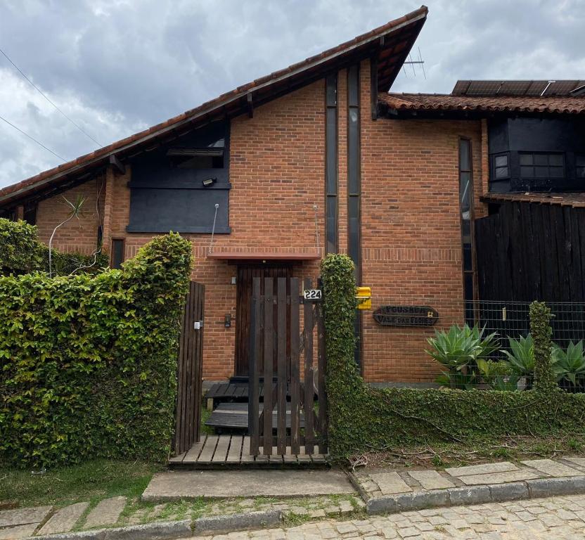 una casa de ladrillo con una puerta de madera delante de ella en Pousada Vale das Flores en Nova Friburgo