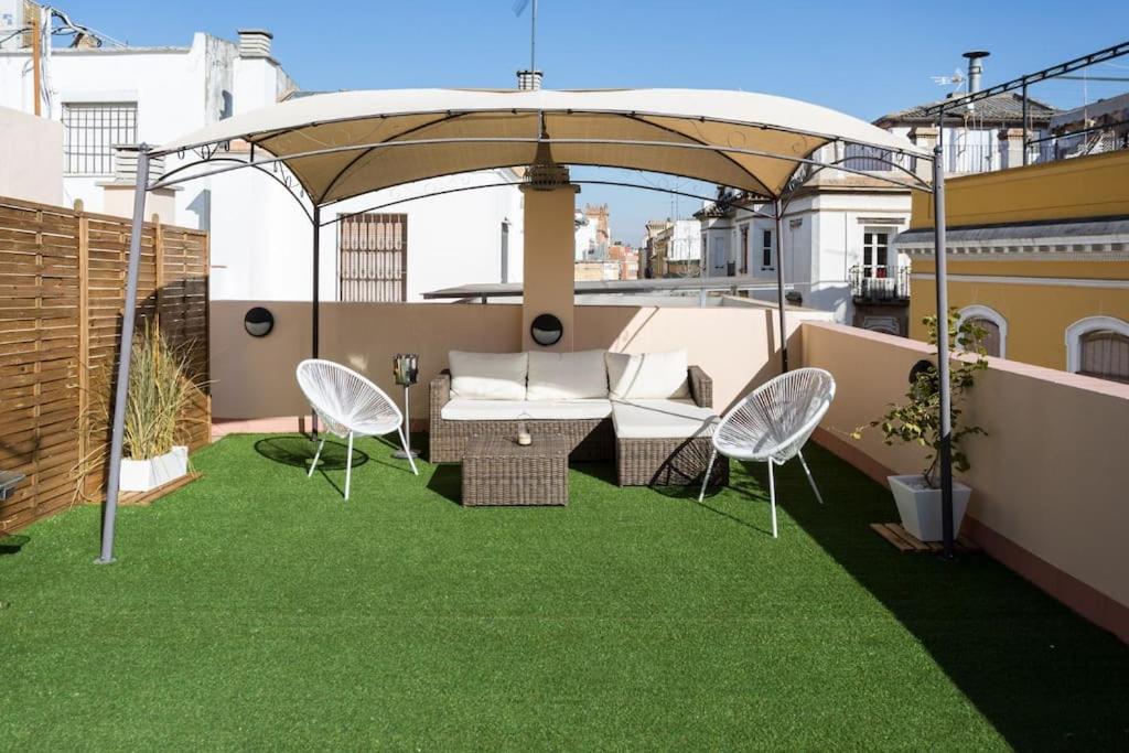a patio with green grass and an umbrella at ESSE Ático. Precioso ático con terraza en pleno centro in Seville