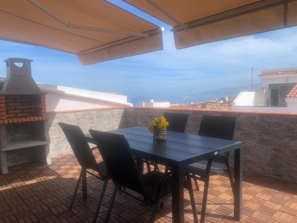 una mesa negra y sillas en un patio con chimenea en Ático Pablo 5, a cinco minutos del Puerto de la Cruz, en Los Realejos