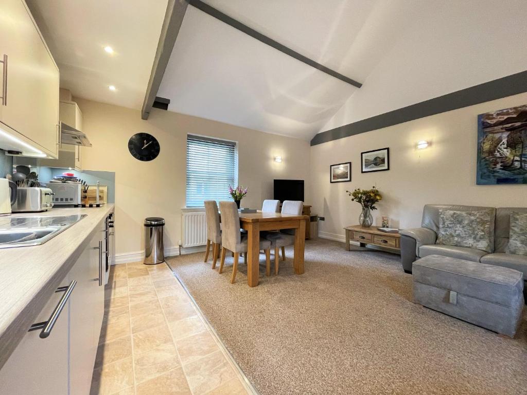 a kitchen and living room with a table and a couch at Arthurs Cottage -Charming Courtyard Cottage in the heart of Kendal, The Lake District in Kendal