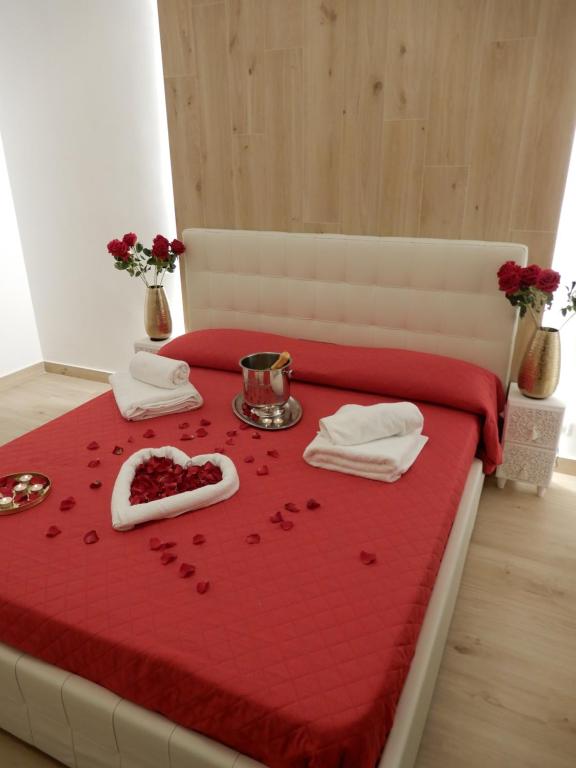 uma cama com uma colcha vermelha com uma bandeja de copas em Caserta Royale Suite em Caserta