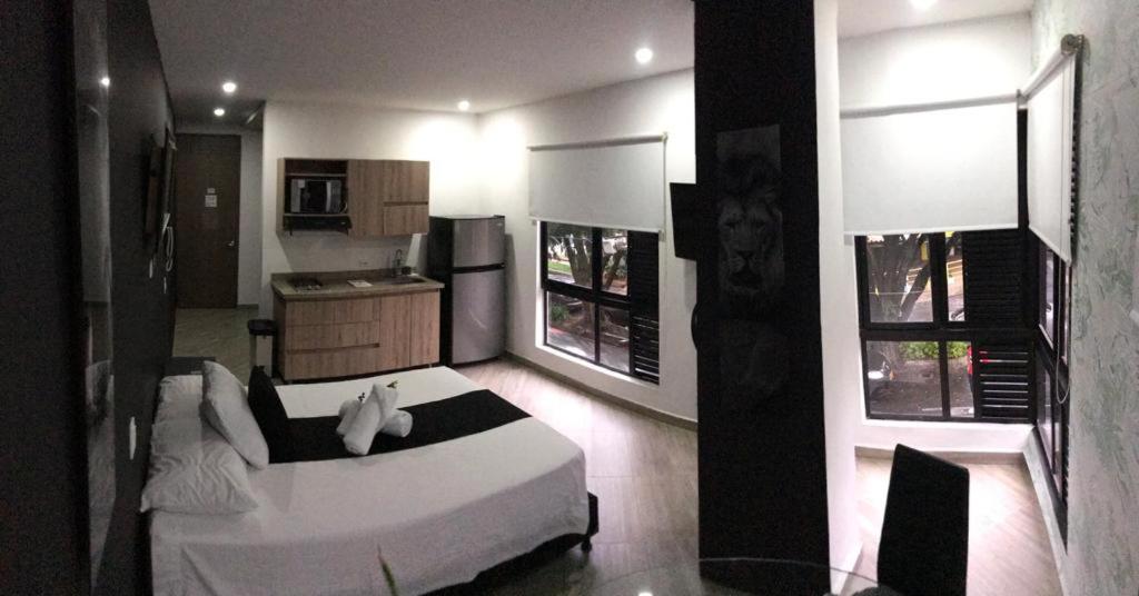 a bedroom with a white bed and a kitchen at Apartahotel Avanti in Medellín
