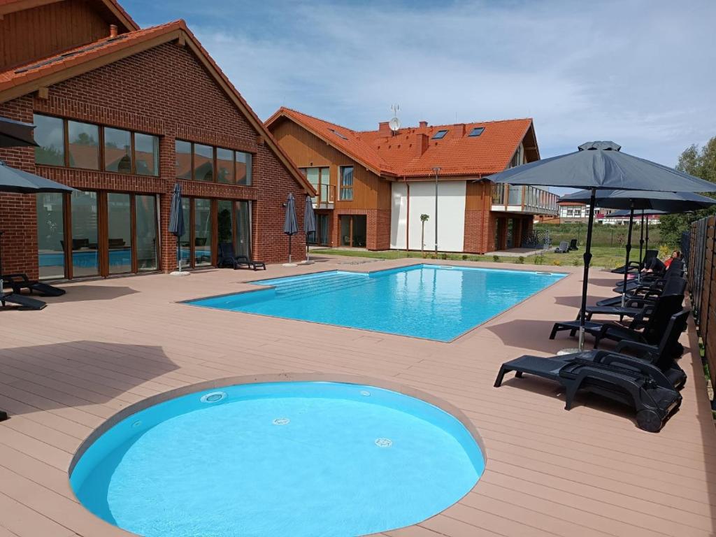 a large swimming pool with chairs and an umbrella at Łebskie Zacisze - apartamenty Łebska Ostoja- Piaskowa in Żarnowska