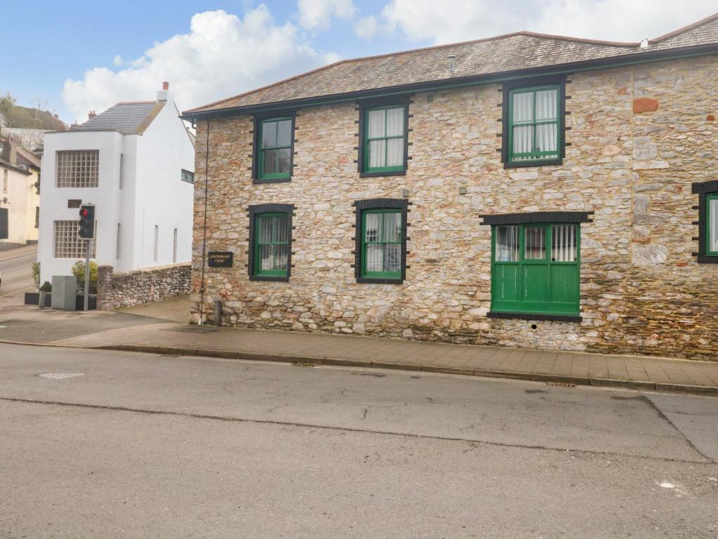 an old stone house with green windows on a street at 1 Greenswood Court in Brixham