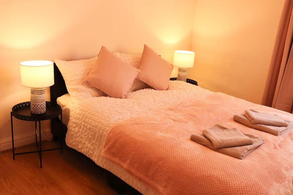 a bedroom with a bed with two lamps on it at Cozy Family Stay with Free Parking and WiFi in Knowsthorpe