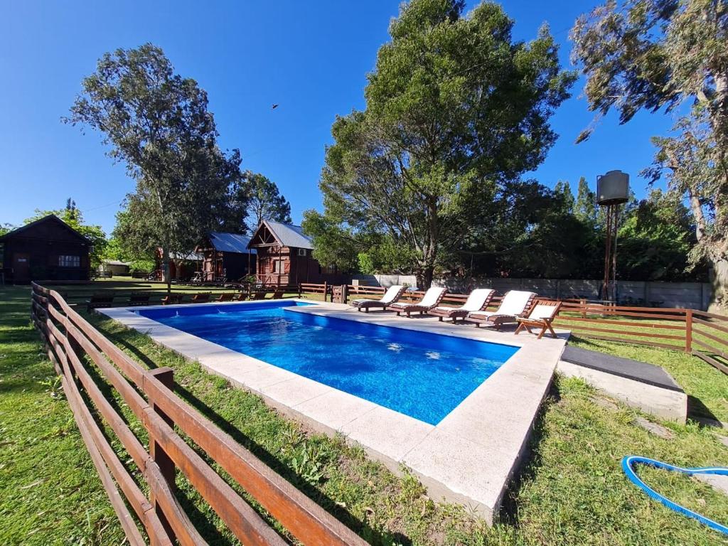 a swimming pool with lounge chairs next to a bench at Cabañas la soñada in Chascomús