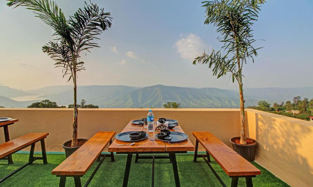 una mesa y bancos en un balcón con palmeras en Treebo Trend Dreamworld, en Panchgani