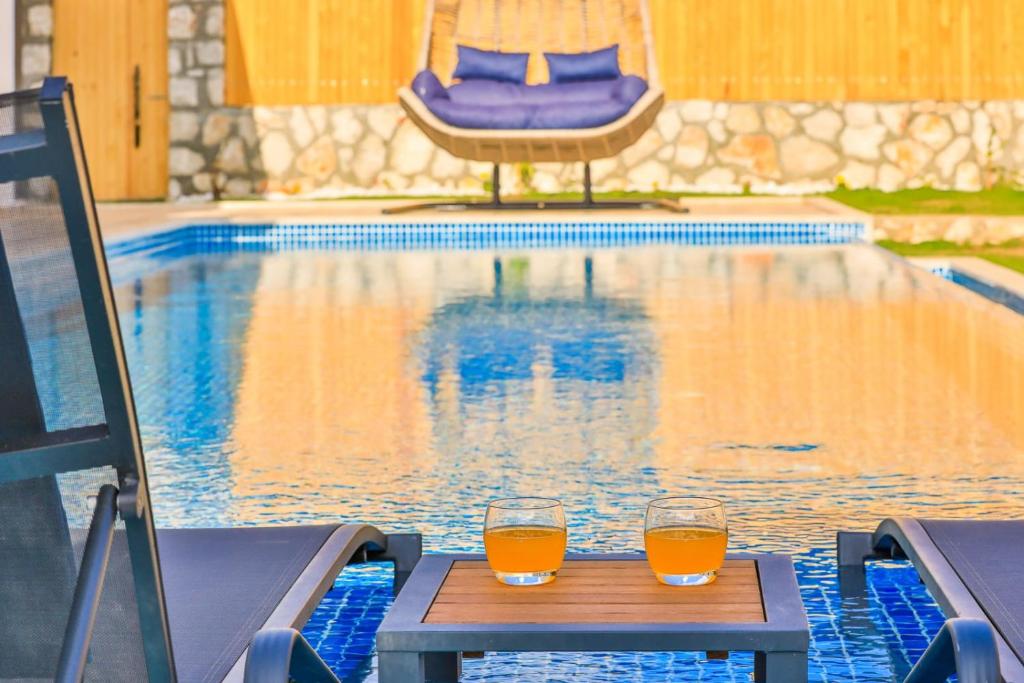 Çayköy的住宿－Exclusive Villas Kalkan，两杯橙汁坐在泳池旁的桌子上