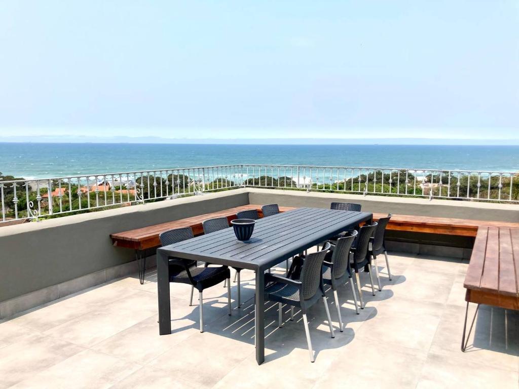 a table and chairs on a balcony with the ocean at Ocean Rocks Villa, Umhlanga in Durban