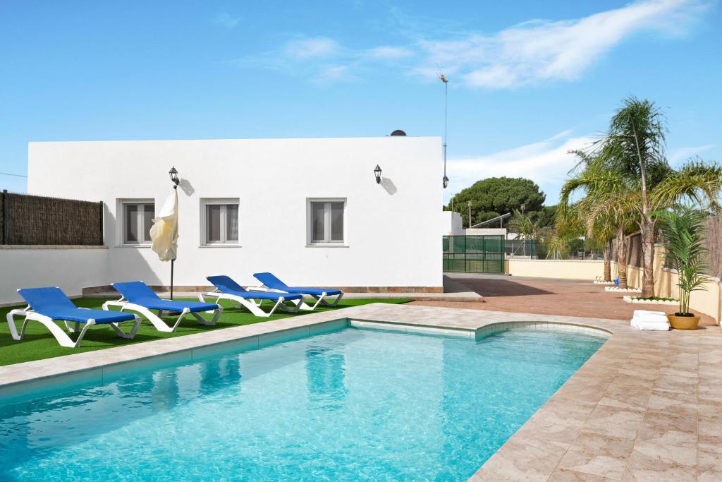 a swimming pool with blue chairs and a house at Villa Montemedio - Paco in El Soto