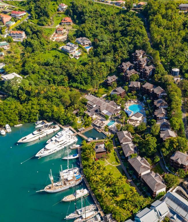 Aerial view of waterfront resort with moored yachts, bungalows, pool, and dense vegetation.