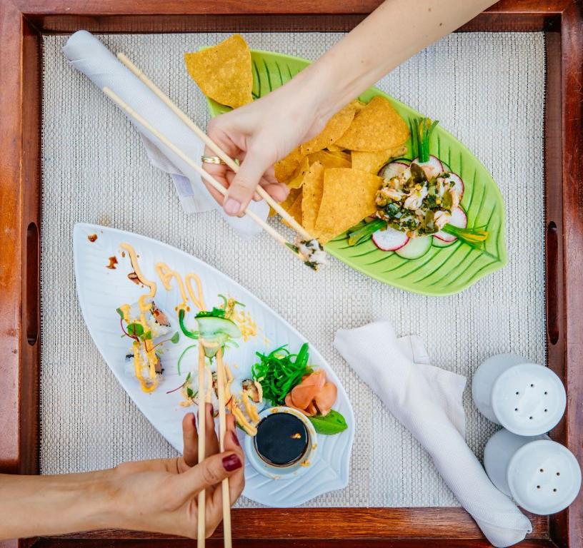 Overhead view of plated Asian cuisine with fresh seafood, vegetables, and sauce on wooden tray.