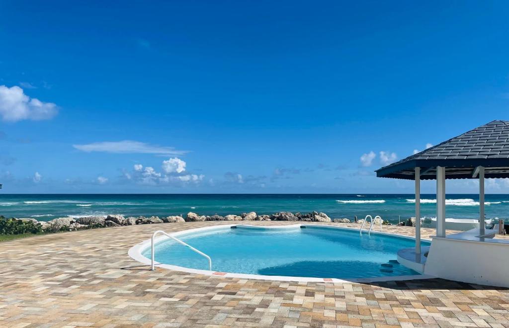 a swimming pool with the ocean in the background at OceanBlue Resort in Christ Church