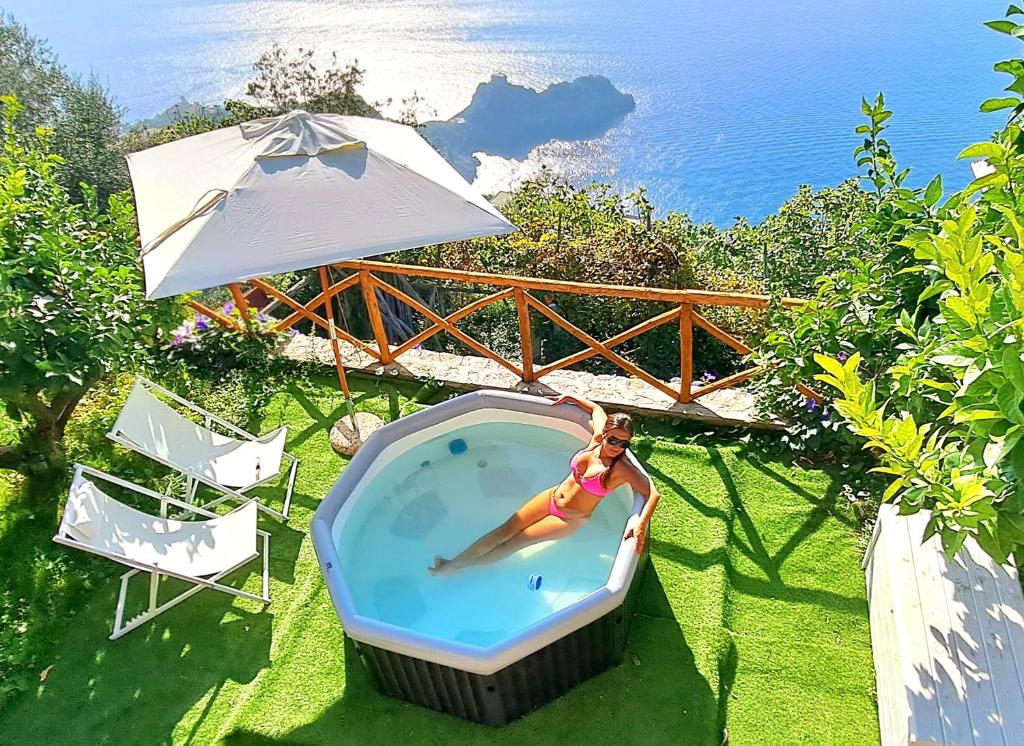 kobieta w basenie z parasolką w obiekcie Relais Amalfi Coast w mieście Conca dei Marini