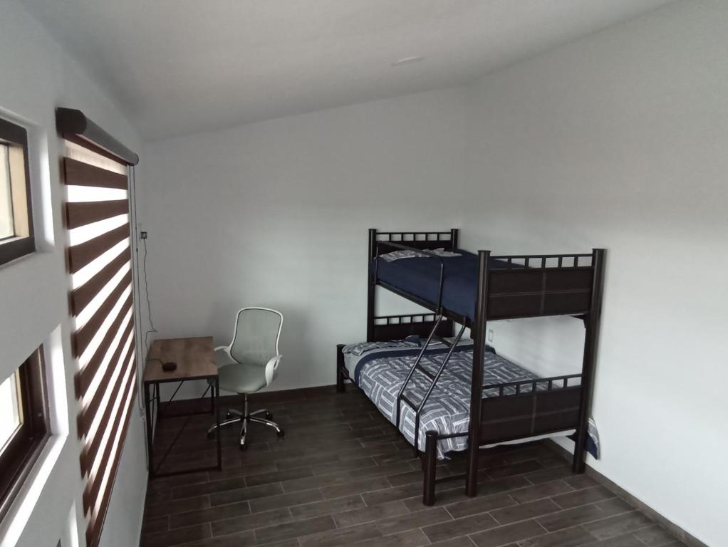 een kamer met 2 stapelbedden en een stoel bij Habitación Chocolate comfort y elegancia en Pachuca 