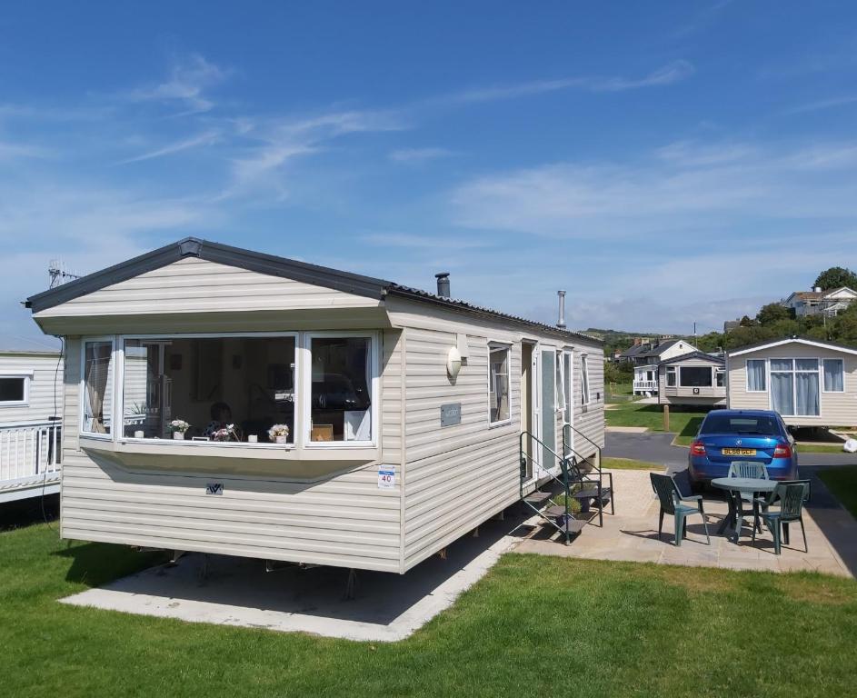 a white caravan parked in a yard with a table and chairs at Clwyd 40 Vacation in Borth