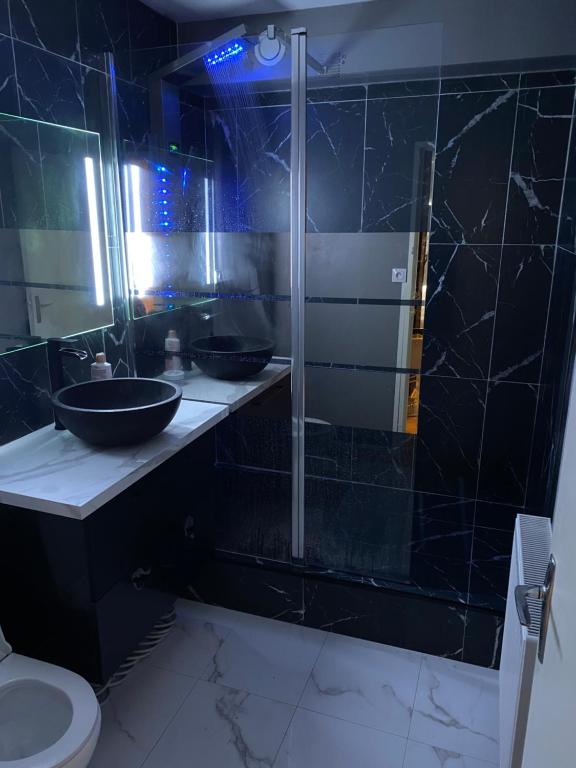 - une salle de bains noire avec deux lavabos et une douche dans l'établissement Suite & Spa Jacuzzi, sauna, lit king size,Netflix, à Montigny-le-Bretonneux