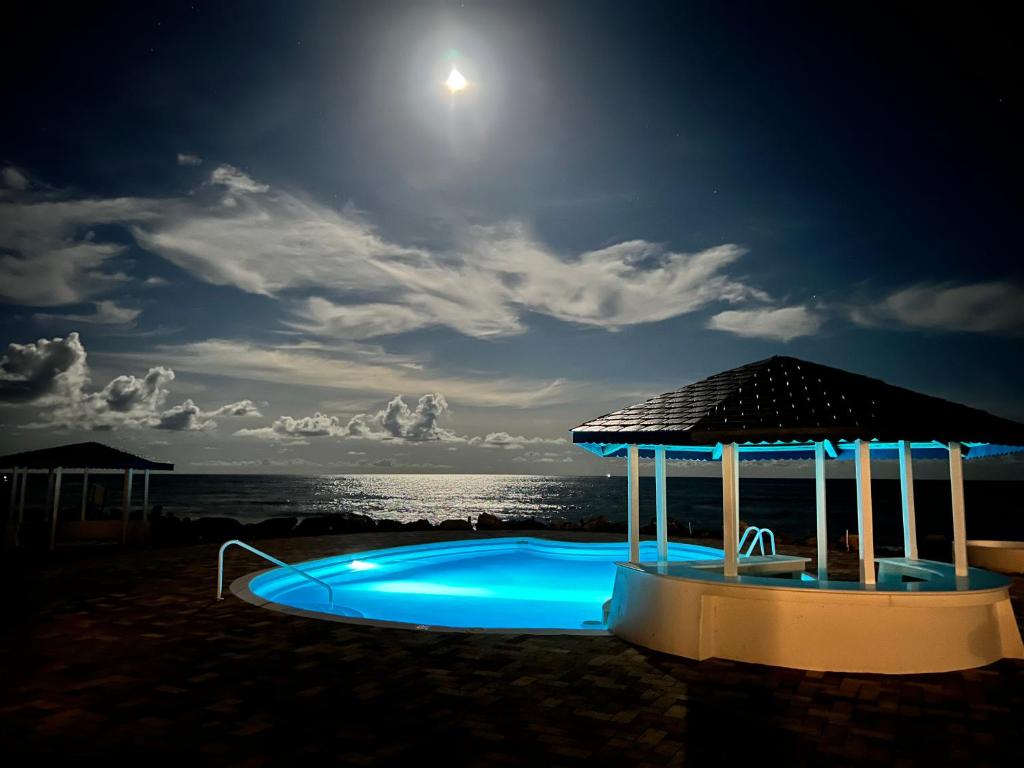 a swimming pool with a gazebo on the beach at night at OceanBlue Resort in Christ Church
