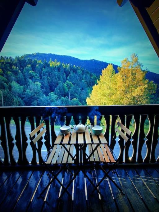 - une table en bois sur un balcon avec vue sur les arbres dans l'établissement Logement 6 pers au cœur des montagnes pyrénéennes linge de maison et papier toilette non fournis, à Boutx