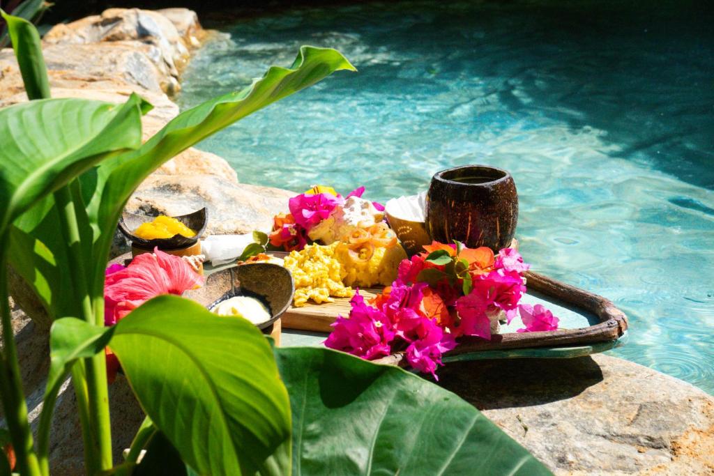 a tray of food and flowers next to a swimming pool at CHALET TROPICAL Hotel & Restaurant-Pizzeria in Las Galeras